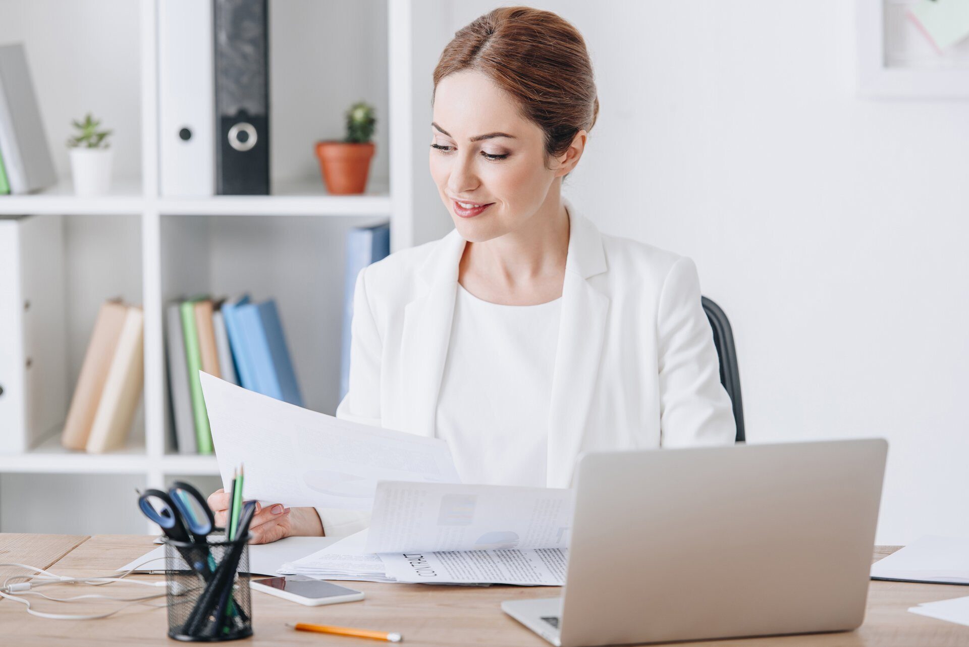 beautiful executive businesswoman working with documents and laptop at workplace in modern office